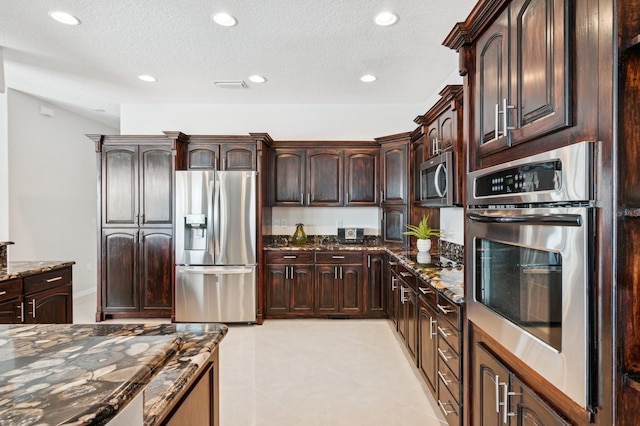 kitchen featuring recessed lighting, visible vents, appliances with stainless steel finishes, dark brown cabinetry, and dark stone counters