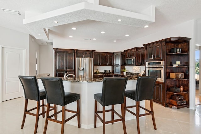 kitchen with light tile patterned flooring, dark brown cabinetry, recessed lighting, a kitchen breakfast bar, and appliances with stainless steel finishes