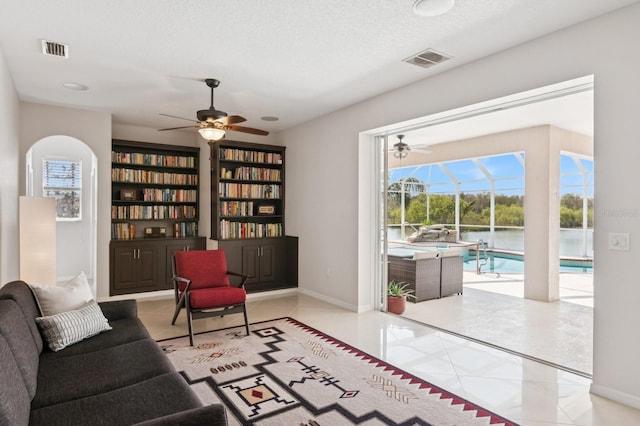 living room featuring a sunroom, visible vents, a textured ceiling, and tile patterned floors