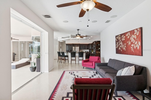 living room with light tile patterned floors, visible vents, and baseboards