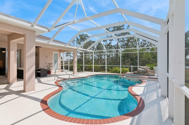 view of pool with a patio area, a pool with connected hot tub, and glass enclosure