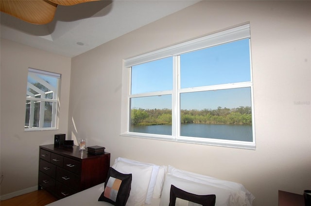 bedroom with a water view, baseboards, and multiple windows