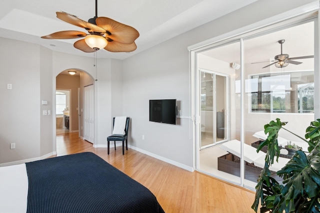 bedroom featuring arched walkways, wood finished floors, a ceiling fan, and baseboards