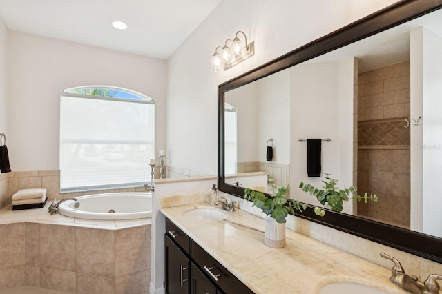 bathroom featuring double vanity, a tub with jets, and a sink