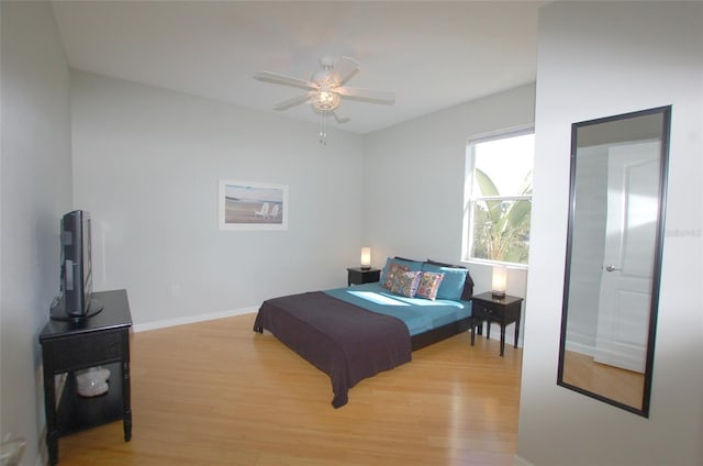 bedroom with light wood finished floors, a ceiling fan, and baseboards