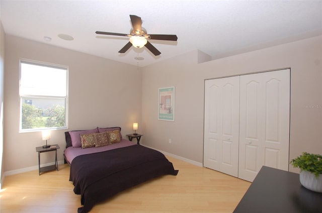 bedroom with light wood finished floors, a closet, a ceiling fan, and baseboards