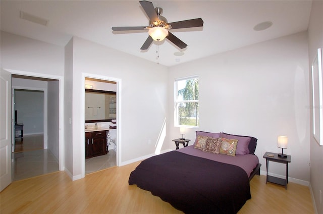 bedroom featuring ensuite bathroom, light wood-style flooring, and baseboards