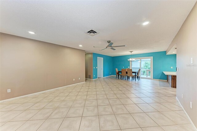 spare room featuring visible vents, light tile patterned flooring, a textured ceiling, baseboards, and ceiling fan with notable chandelier