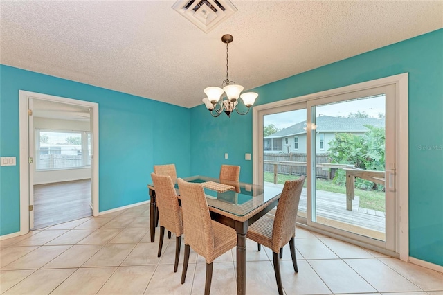 dining area with light tile patterned floors, visible vents, a textured ceiling, and an inviting chandelier