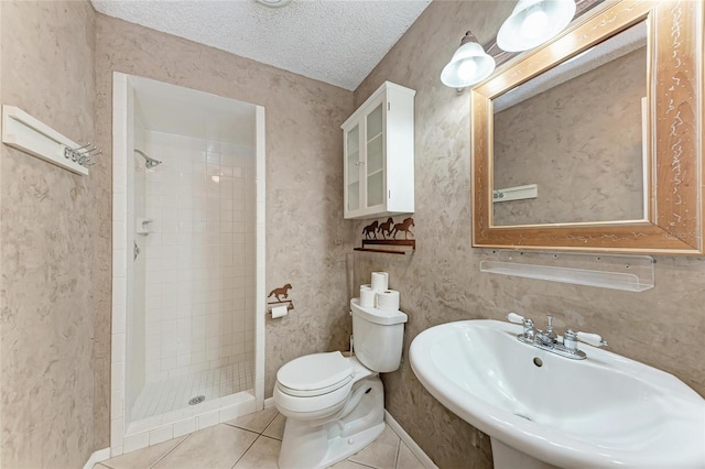 bathroom with a textured ceiling, toilet, a sink, tile patterned floors, and a stall shower