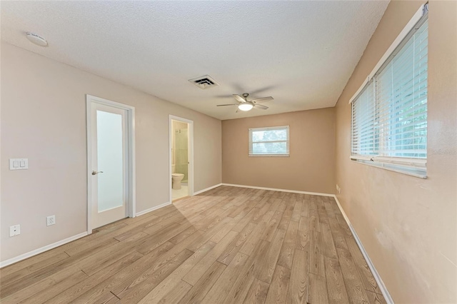 empty room featuring light wood finished floors, visible vents, baseboards, ceiling fan, and a textured ceiling