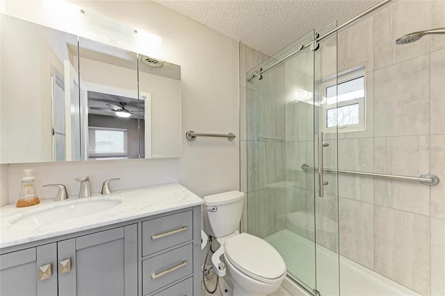 full bath with toilet, a shower stall, a textured ceiling, and vanity