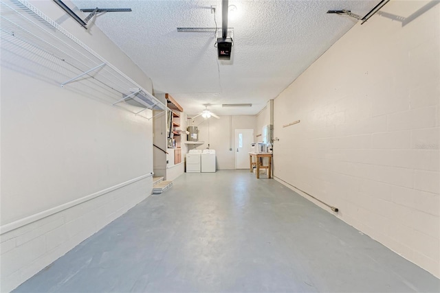 garage with a garage door opener, concrete block wall, and washing machine and clothes dryer