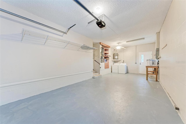 garage featuring concrete block wall, water heater, separate washer and dryer, and a garage door opener