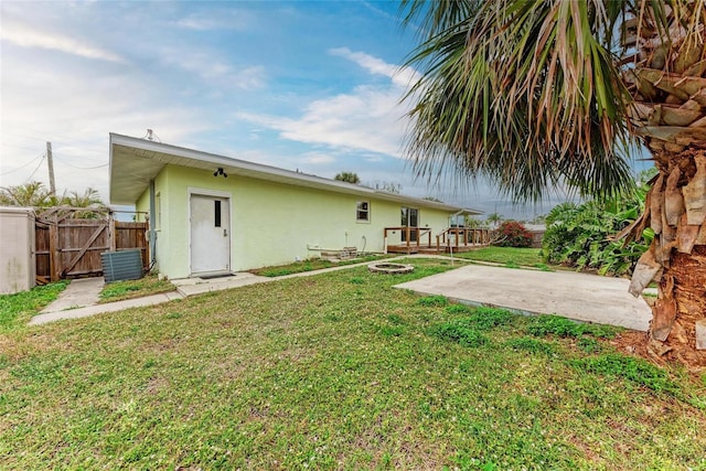 back of house featuring a yard, a patio, central air condition unit, stucco siding, and fence