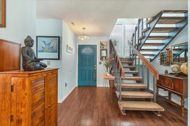 entryway featuring visible vents, stairway, a textured ceiling, wood finished floors, and baseboards