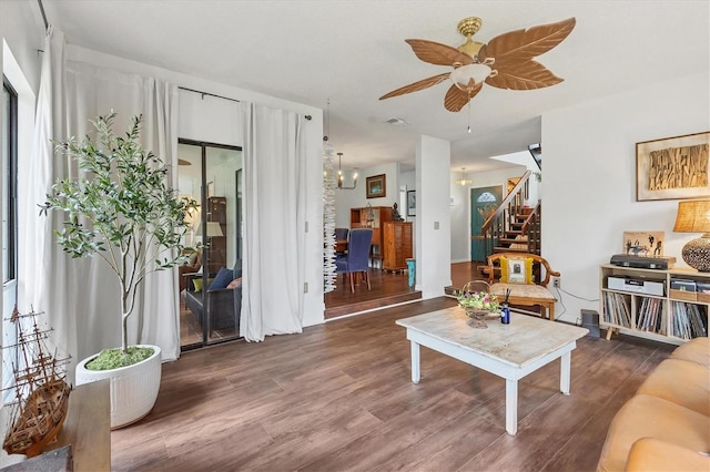 living room with stairs, visible vents, wood finished floors, and ceiling fan with notable chandelier