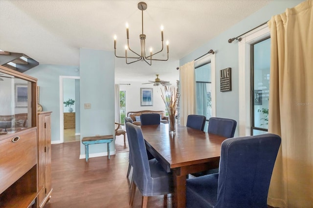 dining space with dark wood-style flooring, a notable chandelier, a textured ceiling, and baseboards