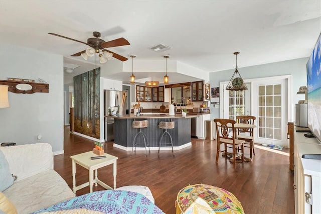 living area with dark wood-style flooring, visible vents, baseboards, vaulted ceiling, and a ceiling fan