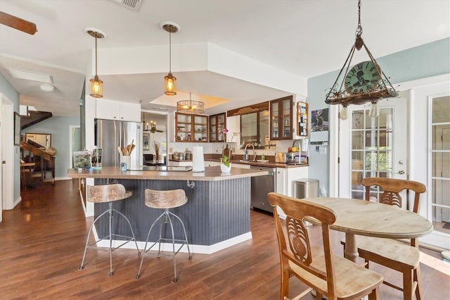 kitchen with a center island, dark wood finished floors, stainless steel appliances, glass insert cabinets, and a sink