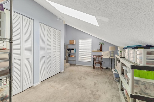 interior space with a textured ceiling, vaulted ceiling with skylight, and baseboards