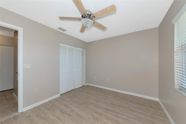 unfurnished bedroom with ceiling fan, light wood-style flooring, visible vents, baseboards, and a closet