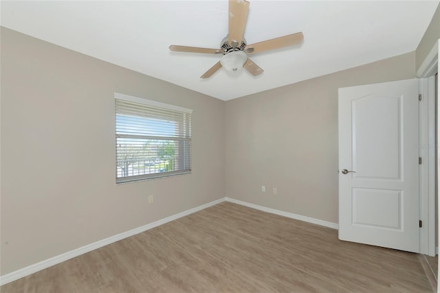 spare room featuring light wood-style floors, baseboards, and a ceiling fan