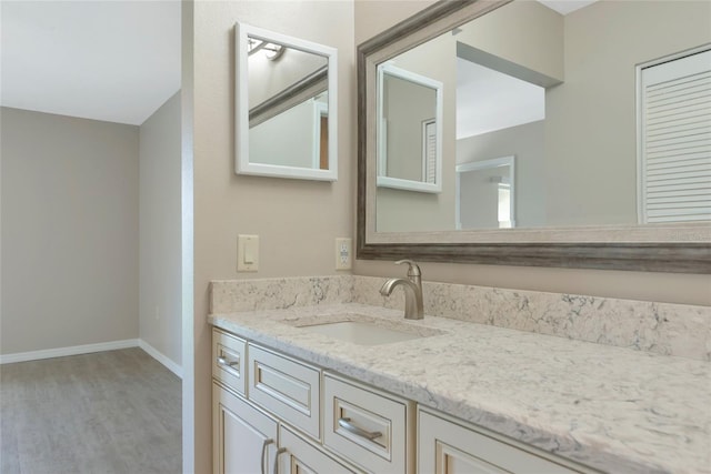 bathroom with wood finished floors, vanity, and baseboards