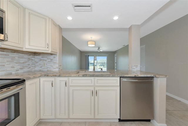 kitchen featuring light stone counters, appliances with stainless steel finishes, visible vents, and tasteful backsplash