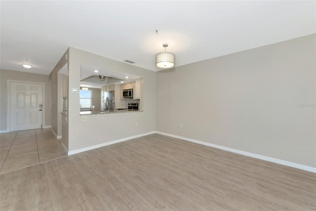 unfurnished living room featuring light wood-style flooring, visible vents, and baseboards