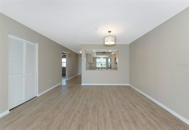 unfurnished living room featuring light wood-style flooring, baseboards, and a sink