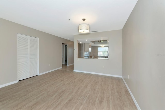 spare room with light wood finished floors, visible vents, baseboards, and a sink