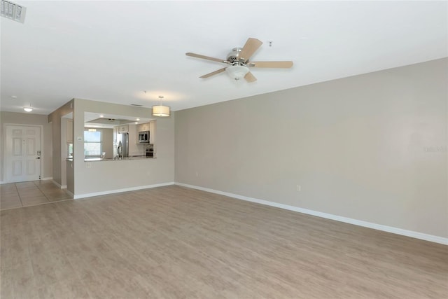 unfurnished living room with light wood-style floors, visible vents, baseboards, and a ceiling fan