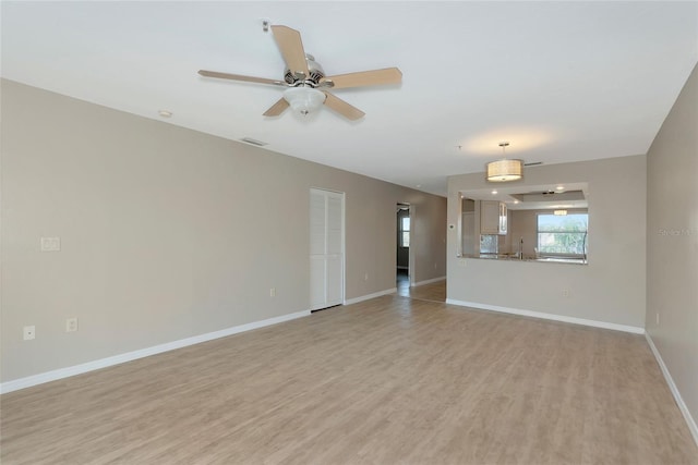 unfurnished living room with light wood-style flooring, a sink, visible vents, and baseboards