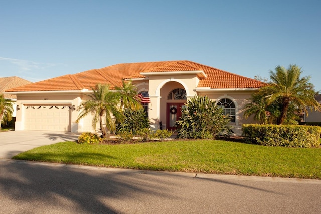 mediterranean / spanish house featuring stucco siding, a front yard, a garage, driveway, and a tiled roof