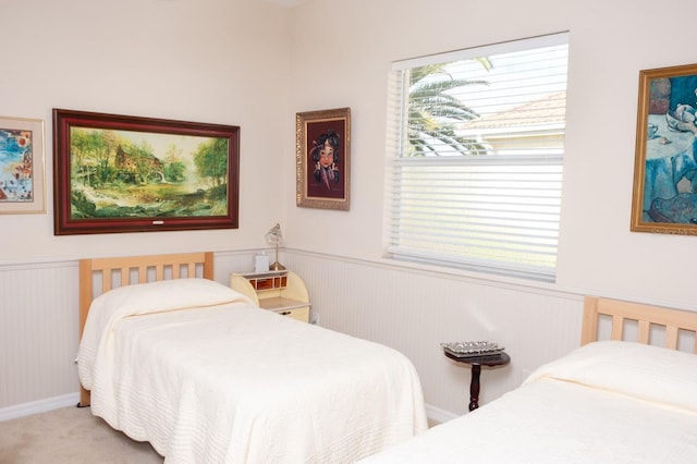 carpeted bedroom featuring a wainscoted wall