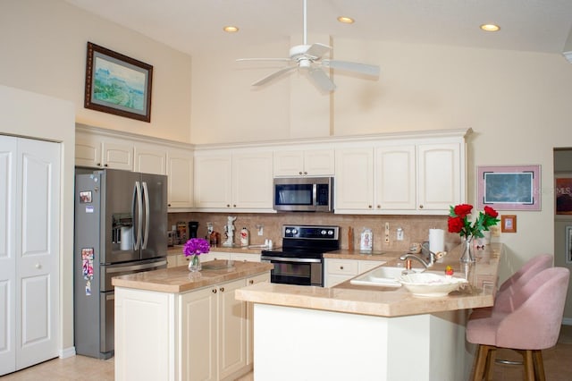 kitchen with a sink, a ceiling fan, a peninsula, stainless steel appliances, and decorative backsplash