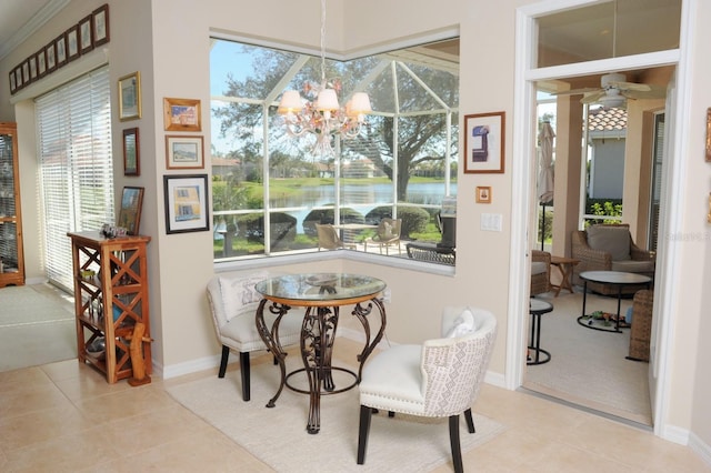 tiled dining area with a water view, baseboards, and ceiling fan with notable chandelier