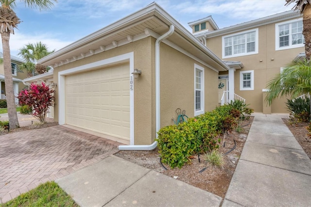 exterior space with decorative driveway, a garage, and stucco siding