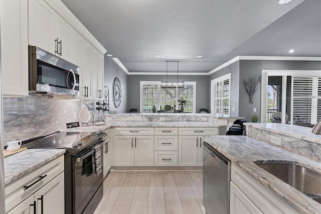 kitchen with backsplash, a peninsula, stainless steel appliances, white cabinetry, and a sink