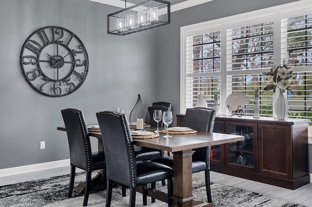 dining room featuring baseboards, ornamental molding, and light wood finished floors