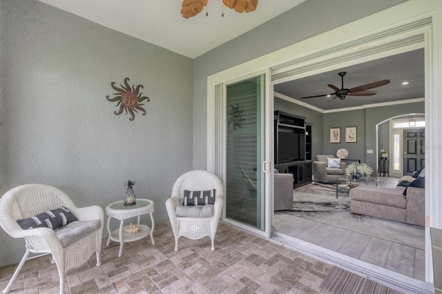 sunroom featuring a ceiling fan and arched walkways