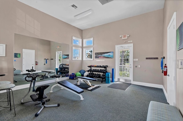 gym featuring visible vents, baseboards, and a towering ceiling