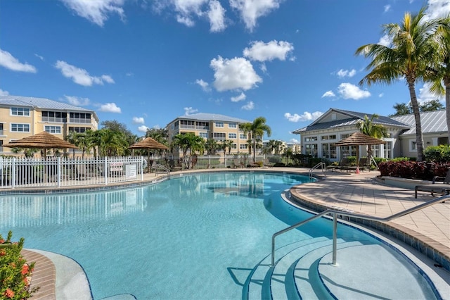 community pool with a patio area and fence