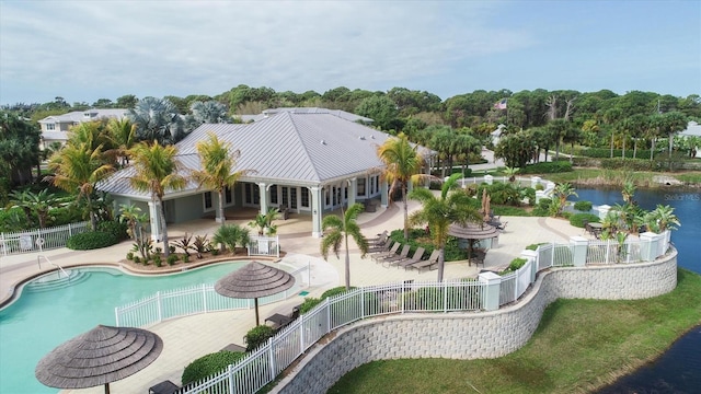 exterior space featuring a water view, fence, a community pool, metal roof, and a patio area