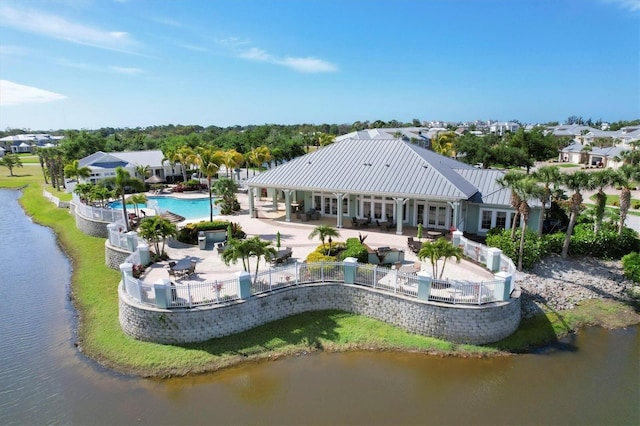 rear view of property with metal roof, a water view, fence, and a patio area