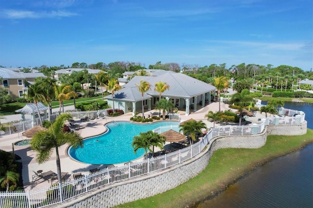 community pool featuring a water view, fence, and a patio area