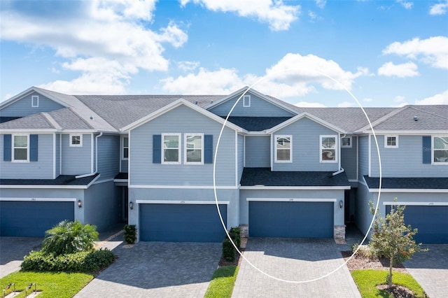 view of property with a garage, roof with shingles, driveway, and stucco siding