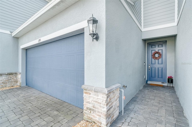 exterior space featuring a garage, stone siding, and stucco siding