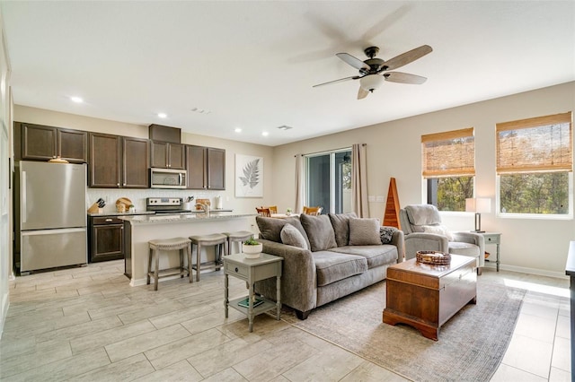 living area featuring baseboards, a ceiling fan, and recessed lighting